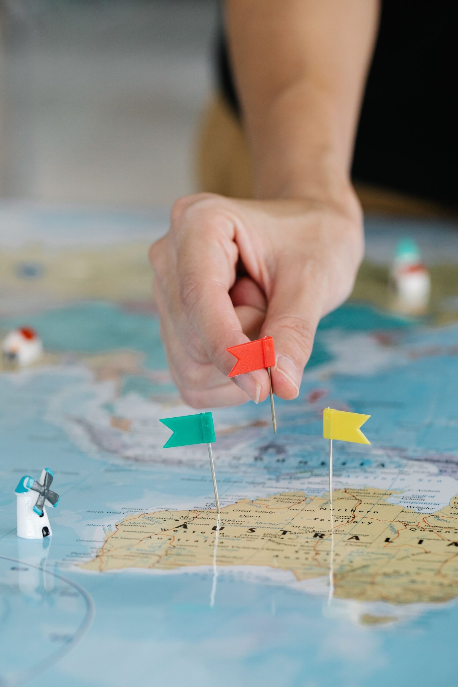 Hand placing a colored location pin flag on a map, representing multiple business locations